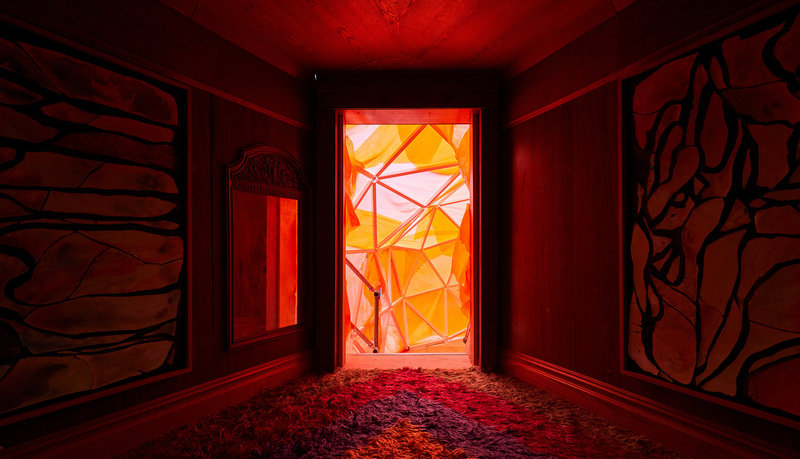 an orange geodesic surface glows beyond the threshold of a door