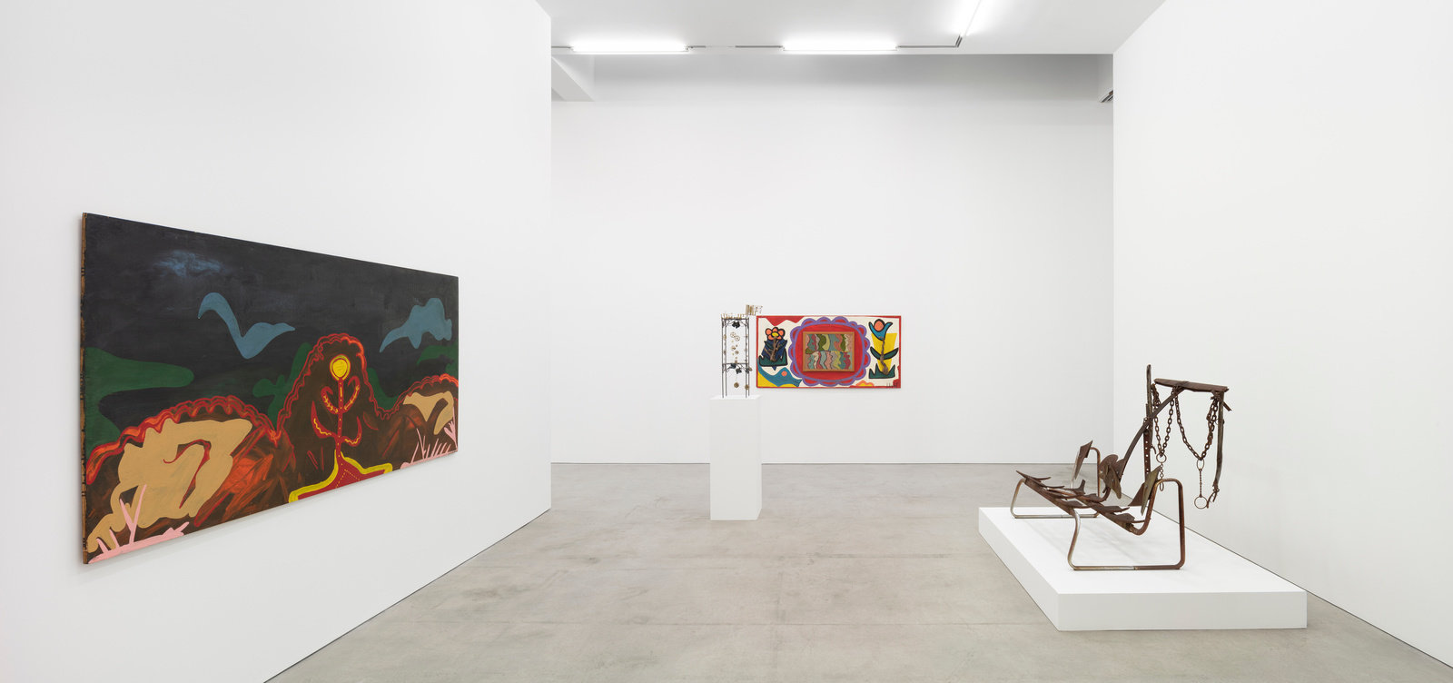 An installation view of two paintings by Joe Light and two sculptures by Joe Minter. 
