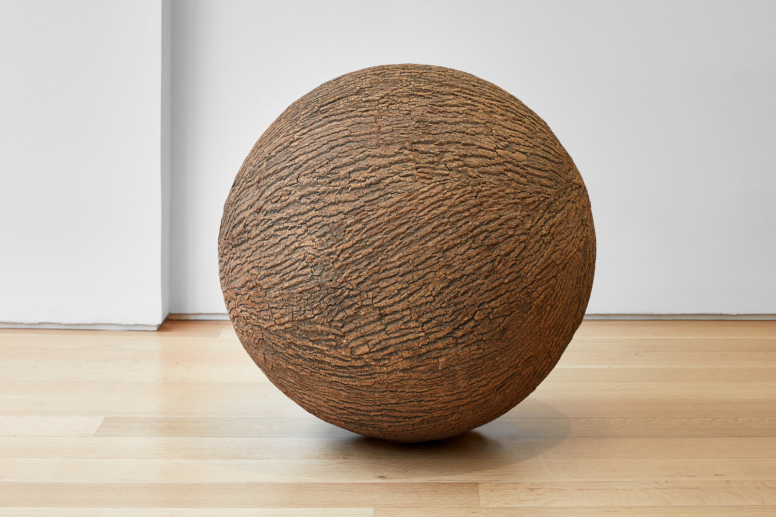 A spherical sculpture made of wood and bark that resembles a tree trunk by Lars Fisk. 