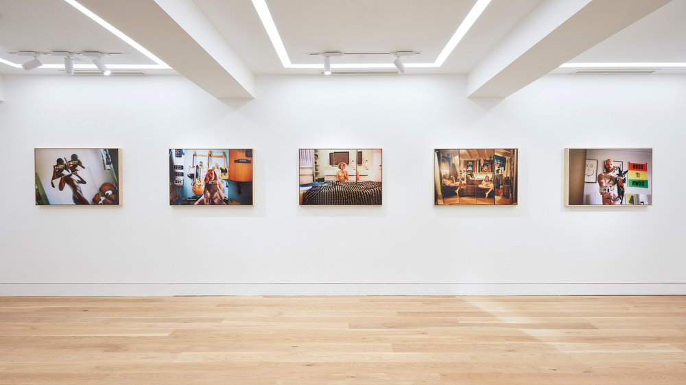 An installation view of five Ryan McGinley photographs hung horizontally on the wall. 